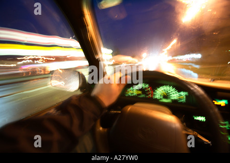 Interior view of person driving at night with lights blurring by.  Shot from drivers perspective. Stock Photo