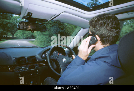 Man driving car whilst using a mobile phone Stock Photo