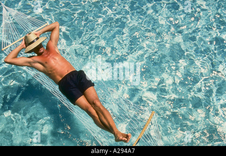 Man relaxing in hammock over water Stock Photo