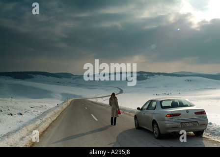 Woman Stranded on a Isolated Road In Winter after Her Car Runs Out of Fuel Stock Photo