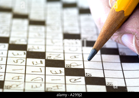 closeup view of hand and pencil working on crossword puzzle Stock Photo