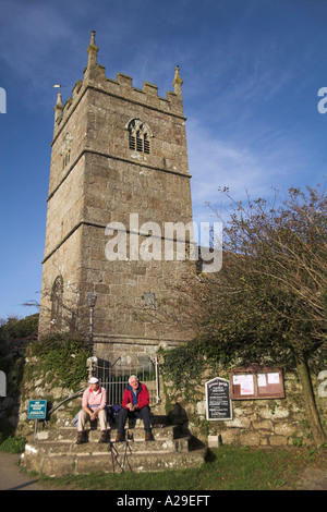 south west coast path walkers waiting for bus sat on steps of ParisParish Church of St Senara Zennor village Penwith Cornwall uk Stock Photo