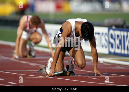 Two male relay runners on their starting blocks preparing themselves before a race Stock Photo