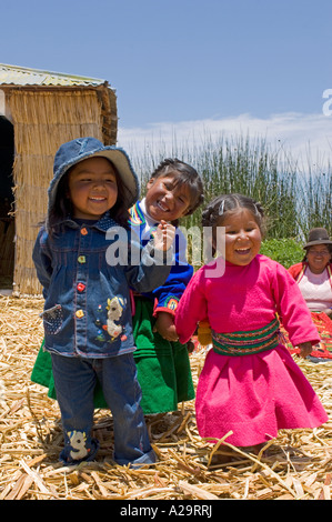 Local children on one of the reed islands of lake Titicaca playing and laughing pose for the camera. Stock Photo
