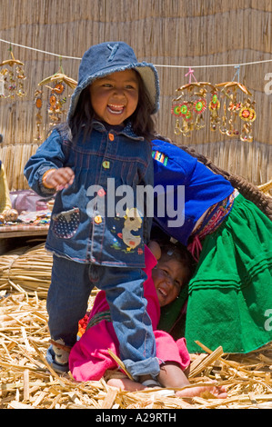 Local children on one of the reed islands of lake Titicaca playing and laughing pose for the camera. Stock Photo