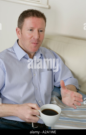young man holding a cup of coffee and listening Stock Photo