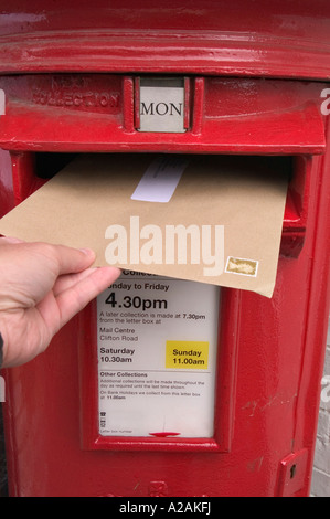 Sending a letter, posting a letter into a red uk postbox Stock Photo