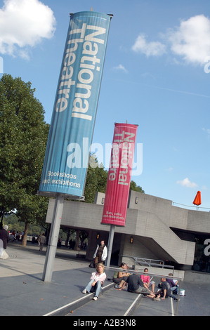 The National Theatre, South Bank, London, England with multi-coloured banners and tourists relaxing Stock Photo