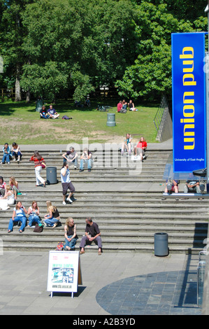 Students relaxing on steps in the sunshine on campus at the University of East Anglia, UEA, Norwich, UK Stock Photo