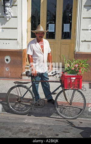 Traditional flower seller standing beside bicycle, Parque Cespedes, Santiago de Cuba, Cuba Stock Photo