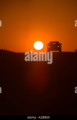 Car Silhouette And Sun At Sunset On Highway, USA Stock Photo