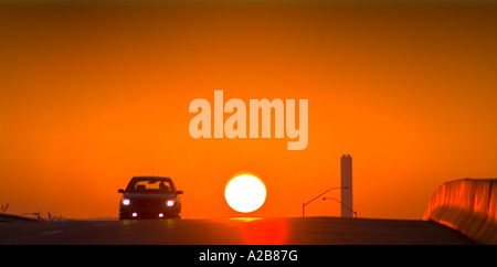 Car Silhouette And Sun At Sunset On Highway, USA Stock Photo