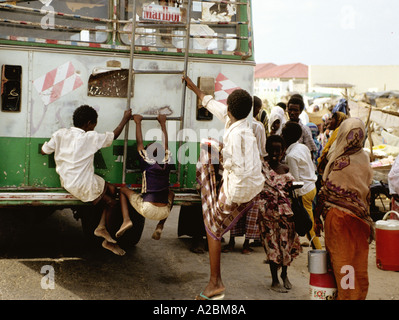YOUNG BOYS  HANG ON TO A MOVING BUS IN MOGADISHU SOMALIA Stock Photo