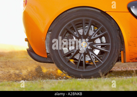 Close-up of Lotus Exige car back wheel kicking up dirt and gravel Stock Photo