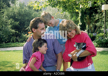 A young mother cuddles a kitten lawn as her husband two children 5-7 years year old look parent family domestic cat young person people  POV MR © Myrleen Pearson Stock Photo