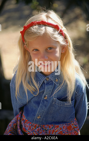 Portrait 8-10 year old young girl smiling shy sweet sunlight smiling looking up at camera  casual casuals dress denim clothes headband outside MR © M Stock Photo