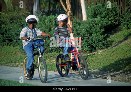 Children Child riding bike bikes bicycle multi racial diversity multicultural cultural two suburban boys 8-10 year years old safety United States Stock Photo