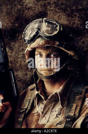 Close up of a military soldier wearing camouflage and face paint while holding a machine gun in his hand Stock Photo