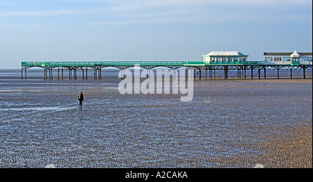 Man walking on the beach at low tide near the pier at Lytham St Annes Stock Photo