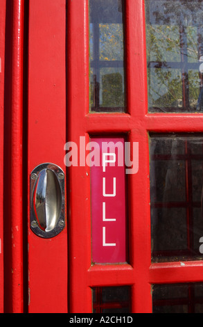 BT red old telephone box payphone box pull door handle on a public phone box UK Stock Photo