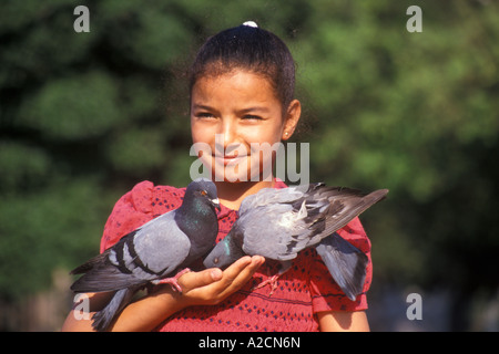 young Spanish girl feeding two pigeons at the Placa de Catalunya in Barcelona in Spain Stock Photo