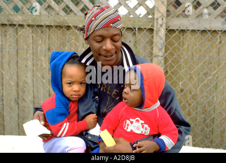 African American dad holding sons age 30 and 2. In the Heart of the Beast May Day Festival and Parade Minneapolis Minnesota USA Stock Photo