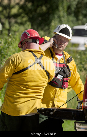 Two firefighters talking on cell phones a wildland fire Stock Photo