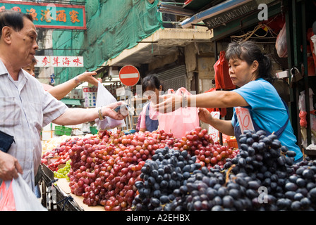 dh Jordan fruit market YAU MA TEI HONG KONG Chinese Stallholder seller grapes to customer display kowloon people street stall greengrocer owner local Stock Photo