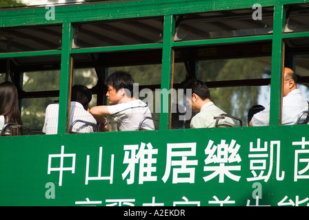 dh  TRAM HONG KONG Passengers in upper deck of green public transport tram calligraphy advert Stock Photo