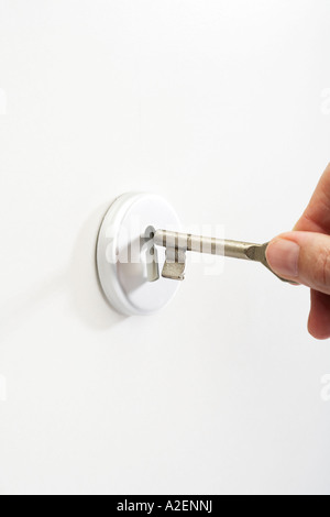 Hand putting key in keyhole, close-up Stock Photo