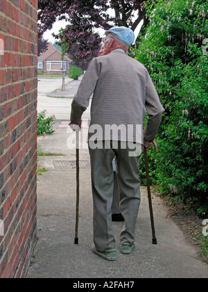 Frail Man Walking With Difficulty With Walking Sticks Stock Photo - Alamy