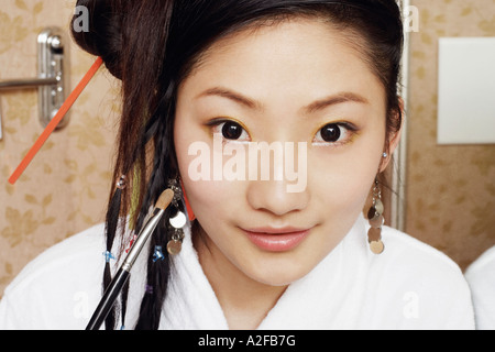 Portrait of a young woman applying make-up on her face Stock Photo