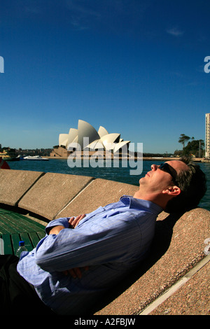 The Sydney Opera House on a beautiful day with man asleep in foreground Stock Photo