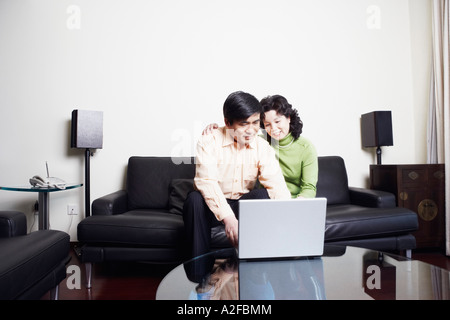 Mature couple sitting on a couch using a laptop Stock Photo