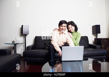Portrait of a mature man sitting on a couch with a mature woman using a laptop Stock Photo