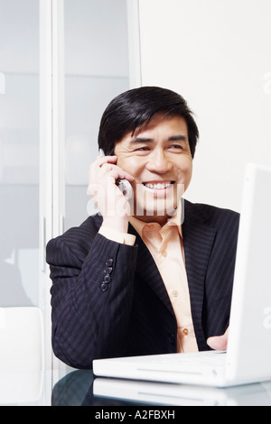 Businessman sitting in front of a laptop talking on a mobile phone