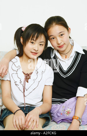 Portrait of two young women sitting together on a couch Stock Photo