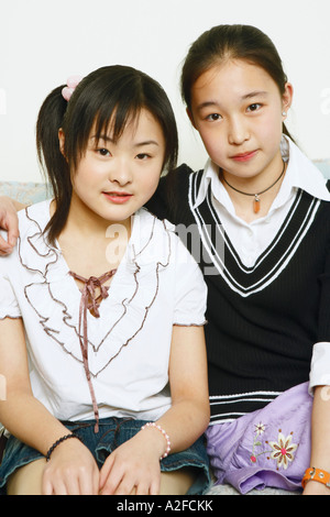 Portrait of two young women sitting together on a couch Stock Photo