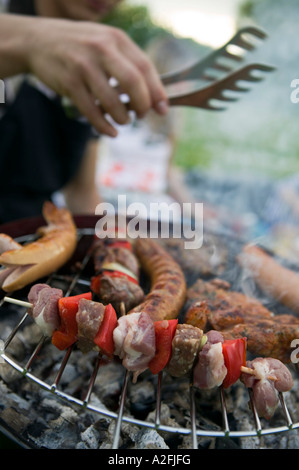 Meat and sausages on grill people in background Stock Photo