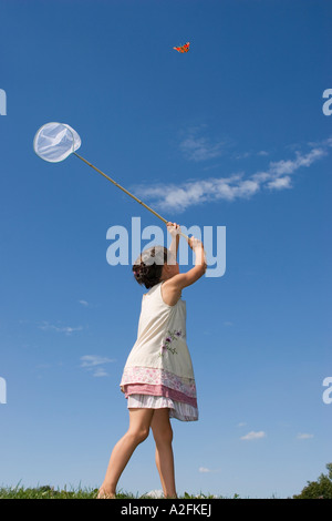 Girl (7-9) holding net, trying to catch butterfly Stock Photo