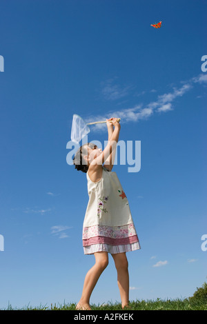 Girl (7-9) holding net, trying to catch butterfly Stock Photo