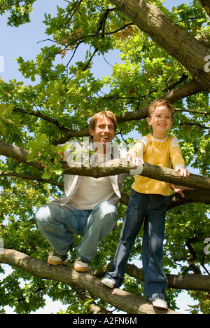 Father and son (4-7) on tree, low angle view Stock Photo