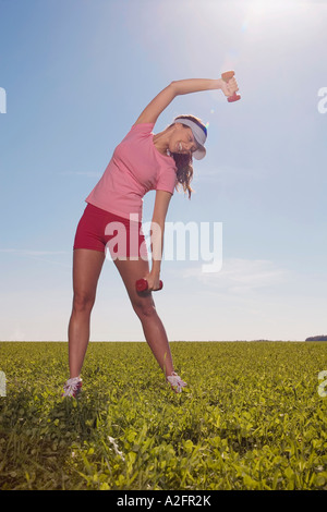 Young woman exercising with dumbbells, stretching Stock Photo