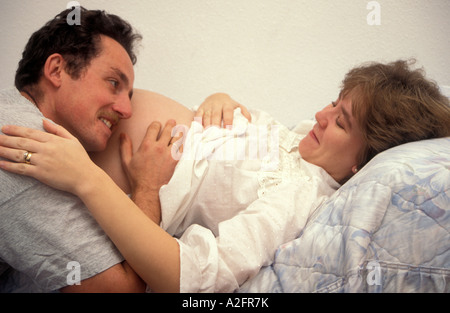 proud husband lying on wife's heavily pregnant tummy Stock Photo