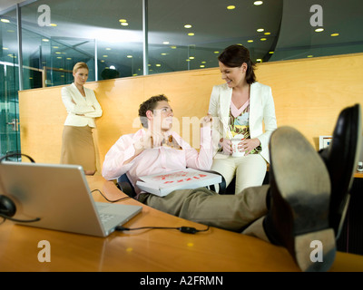 Couple having lunch in office, woman watching Stock Photo