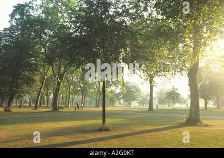 Early morning walkers in among the trees at Kensington Gardens, London Stock Photo