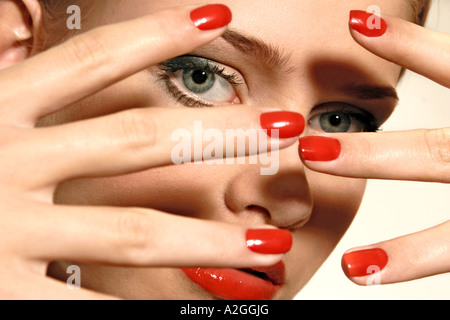1217508 indoor studio young woman 25 30 blonde hand hands cover face finger fingers nail nails polish red manicure cosme Stock Photo