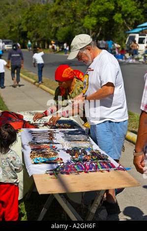 Young Kuna woman sells molas and other crafts to an American tourist at El Valle de Anton Market. Republic of Panama. Stock Photo