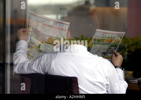 Businessman reading a newspaper behind a window in a Coffee Shop, Hong Kong, SAR Stock Photo