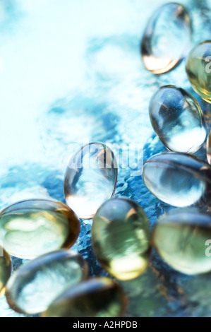 Portrait shot of cod liver oil and star flower oil capsules arranged on textured glass  shot with shallow focus Stock Photo